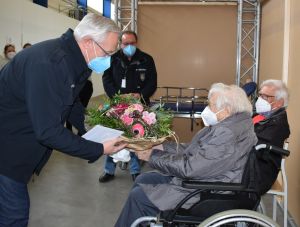 Foto: Agathe Puderbach wird zum 100. Geburtstag geimpft und erhält Blumen vom Landrat.