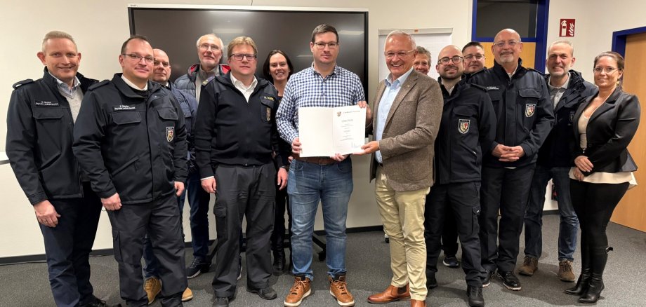 Foto-Unterzeile: Von Landrat Achim Hallerbach wurde Dennis Enders in der Runde der Kolleginnen und Kollegen Organisationsleiter und Leitende Notärzte und in Gegenwart von BKI Holger Kurz als neuer ehrenamtlicher Organisationsleiter vereidigt. Foto: Volker Lemgen / Brand- und Katastrophenschutz Landkreis Neuwied