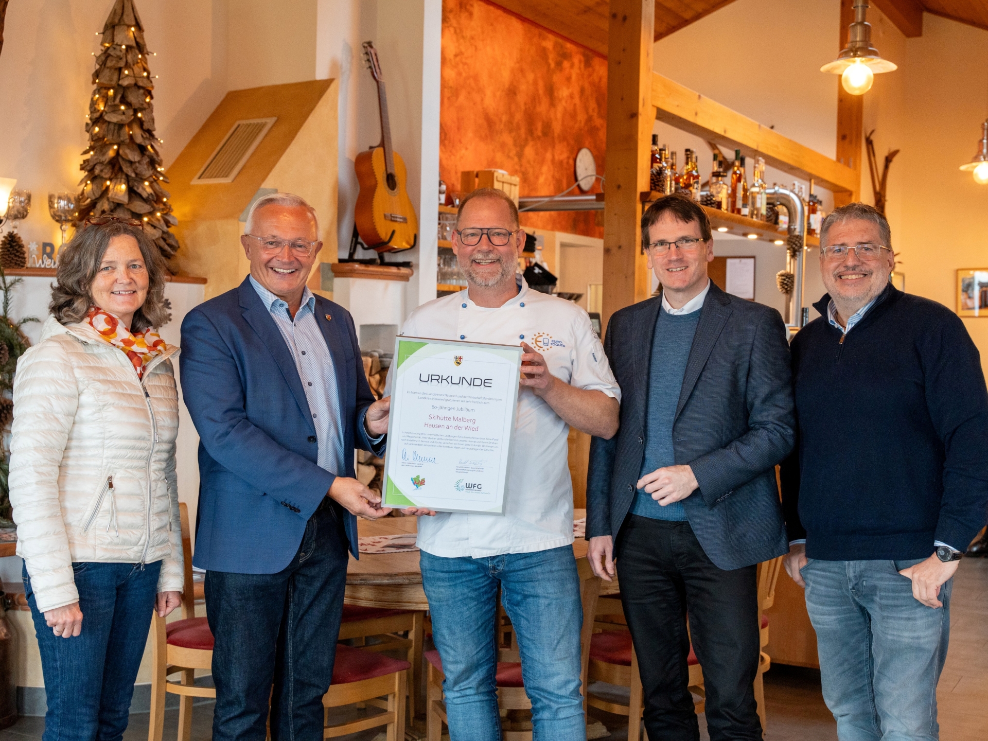 Landrat Achim Hallerbach, Kreiswirtschaftsförderer Harald Schmillen, Naturgenuss-Projektleiter Jörg Hohenadl und die Ortsbürgermeisterin von Hausen, Carmen Boden, gratulierten Jürgen Hühner und dessen Team zu 60 Jahren Skihütte. Foto: Martin Boden / Kreisverwaltung Neuwied
