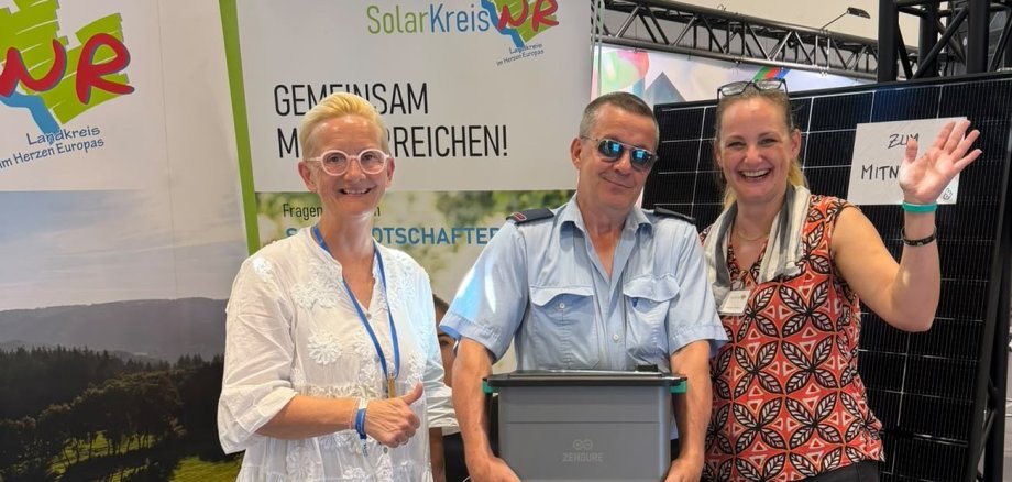 Freuen sich über den Gewinn eines Balkonkraftwerks mit Speicher: der Gewinner aus Niederraden gemeinsam mit Glücksfee Peggy Stüber von der Wirtschaftsförderung Rengsdorf-Waldbreitbach (links) und Kreis-Klimaschutzmanagerin Janine Sieben von der Kreisverwaltung Neuwied bei den VG-Tagen in Waldbreitbach.
Foto: Verena Stüber
Freuen sich über den Gewinn eines Balkonkraftwerks mit Speicher: der Gewinner aus Niederraden gemeinsam mit Glücksfee Peggy Stüber von der Wirtschaftsförderung Rengsdorf-Waldbreitbach (links) und Kreis-Klimaschutzmanagerin Janine Sieben von der Kreisverwaltung Neuwied bei den VG-Tagen in Waldbreitbach. Foto: Verena Stüber