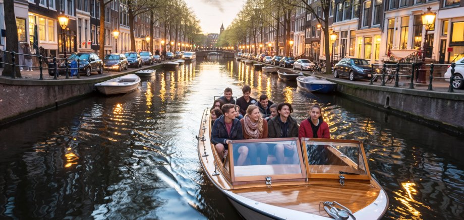 Bildungsfahrt nach Amsterdam. Jugendliche sitzen in einem Boot und fahren durch die Grachten von Amsterdam.
