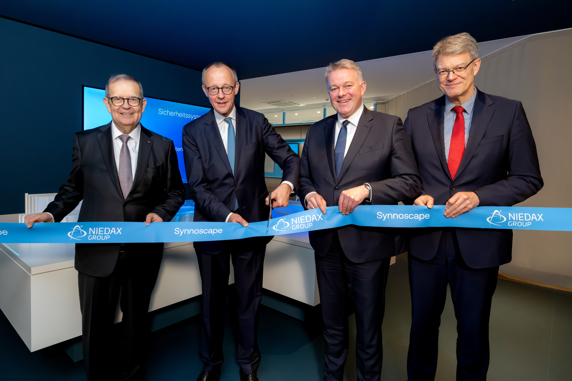 Von links nach rechts: Bruno Reufels (CEO, Niedax Group) und Friedrich Merz (Bundeskanzler der Bundesrepublik Deutschland, MdB) eröffnen im Beisein von Gordon Schnieder (CDU-Fraktionsvorsitzender im Landtag Rheinland-Pfalz, MdL) und Patrick Schnieder (Bundesminister für Verkehr der Bundesrepublik Deutschland, MdB) das Experience Center „Synnoscape“ der Niedax Group am Technologie Campus in Neustadt/Wied-Rahms (Rheinland-Pfalz). Bildquelle: Niedax/Dieter Klaas.