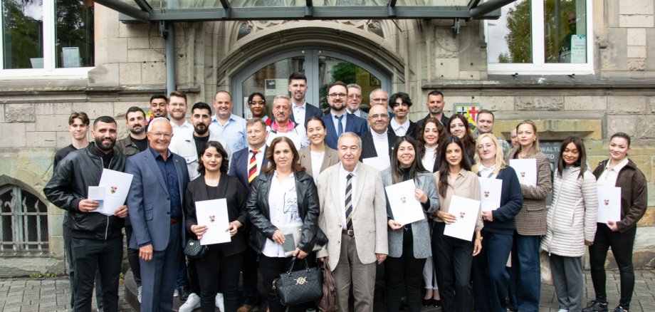 Strahlende Gesichter bei der Einbürgerungsfeier im Max-zu-Wied-Saal: Gemeinsam mit Landrat Achim Hallerbach freuten sich die neuen deutschen Staatsbürgerinnen und Staatsbürger über ihre Einbürgerung im Landkreis Neuwied. Foto: Julia Hinz / Kreisverwaltung Neuwied