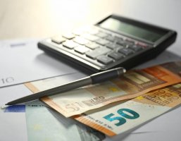 Geldscheine und Taschenrechner auf einem Schreibtisch.