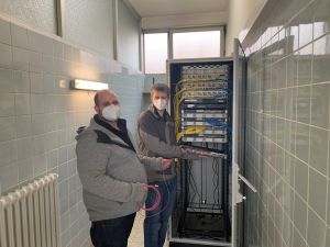 Foto: Alle 25 Schulen des Landkreises werden nach der jetzigen Planung spätestens zum neuen Schuljahr mit einer modernen IT-Infrastruktur ausgestattet sein. Das ist die Kernaussage von Landrat Achim Hallerbach und dem 1. Kreisbeigeordneten Michael Mahlert. Bis zum Sommer 2021 will der Kreis die laufenden Arbeiten abgeschlossen haben. IT-Support-Manager Sebastian Biersch (rechts) kontrolliert mit seinem Kollegen Martin Wagner die Verbindungen am Serverschrank der Maximilian-Kolbe-Schule in Rheinbrohl.