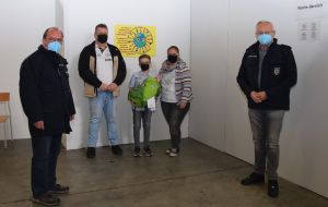 Foto: Mit dem „Sonderpreis der Jury“ würdigten Landrat Achim Hallerbach (ganz rechts im Bild) und Impfkoordinator Werner Böcking (ganz links) das Plakat von Alessio Pothoff das zukünftig den Eingangsbereich im Impfzentrum zieren wird.