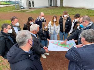 Foto: Freuen sich, dass das Sport-Außengelände des WHG grundsaniert wird: (von links unten im Uhrzeigersinn) Tim Dunker (Schulelternbeirat), Marco David (Fachvorsitz Sport), Landrat Achim Hallerbach, Schulleiter Michael Strauss, Sportlehrerin Jennifer Zunkel, Verbindungslehrer Jörg Eckert Zunkel (Sport), die Schülervertreter Johanna Welle (mit der Hand am Plan), Carlotta Burger, Moritz Huxoll, Fabian Fogel und Sophie Hartstang, sowie Rüdiger David und Beigeordneter Michael Mahlert von der Neuwieder Kreisverwaltung. 
