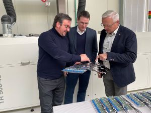 Foto: Colotec-Chef Oliver Nixdorf (von links) stellte Kreis-Wirtschaftsförderer Harald Schmillen und Landrat Achim Hallerbachsein Unternehmen vor. Hier zeigt er Indust-riebauteile mit einer kleinen Platine, die in seinem Haus speziell gereinigt  wird. Foto: Kreisverwaltung Neuwied / Ulf Steffenfauseweh