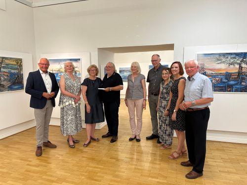 Landrat Achim Hallerbach und Museumsleiterin Jennifer Stein würdigten während der Vernissage das künstlerische Schaffen von Uwe Langnickel, dessen Ausstellung „Wunderschön – Bella Mediterrana“ bis 17. August 2025 im Roentgen-Museum zu sehen ist. Solches Lob vernahmen auch Familie, Freunde, Kunstschüler und die musikalischen Künstler mit Wohlwollen. Foto: Thomas Herschbach