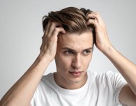 Junger Mann kratzt sich am Kopf