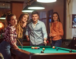 Jugendliche die in einem Jugendtreff Billard spielen.