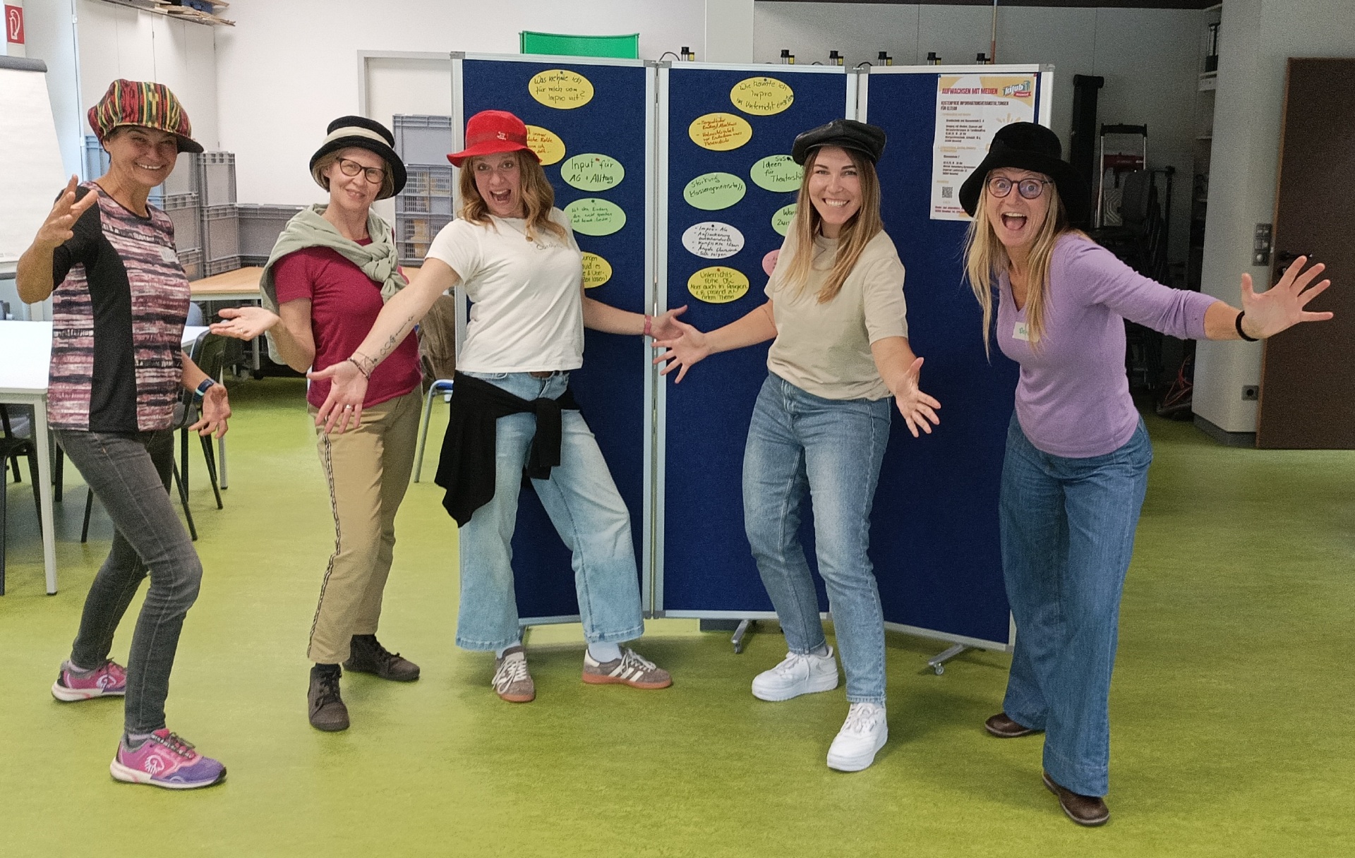 Auf dem Bild sind 5 Frauen zu sehen, die uns die Hände entgegenstrecken und Jede hat einen Hut auf dem Kopf.